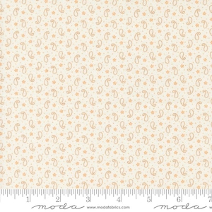 May include: White fabric with a repeating pattern of small orange paisley shapes and tiny orange flowers. The fabric is shown with a ruler marked in inches.