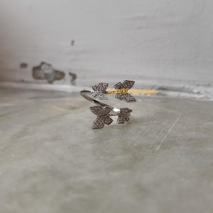 May include: Silver ring featuring three butterfly designs set with clear sparkling stones.