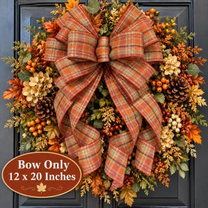 May include: A decorative wreath featuring a large, central plaid bow in shades of orange, brown, and green, surrounded by artificial autumn foliage, pinecones, and berries. An oval sign states: Bow Only 12 x 20 Inches.