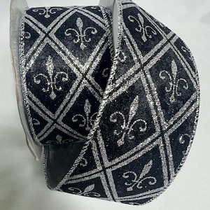 May include: A roll of black ribbon with a silver glitter fleur-de-lis pattern. The ribbon features a diamond grid design with the fleur-de-lis symbol in each diamond. The edges of the ribbon are also trimmed with silver glitter.