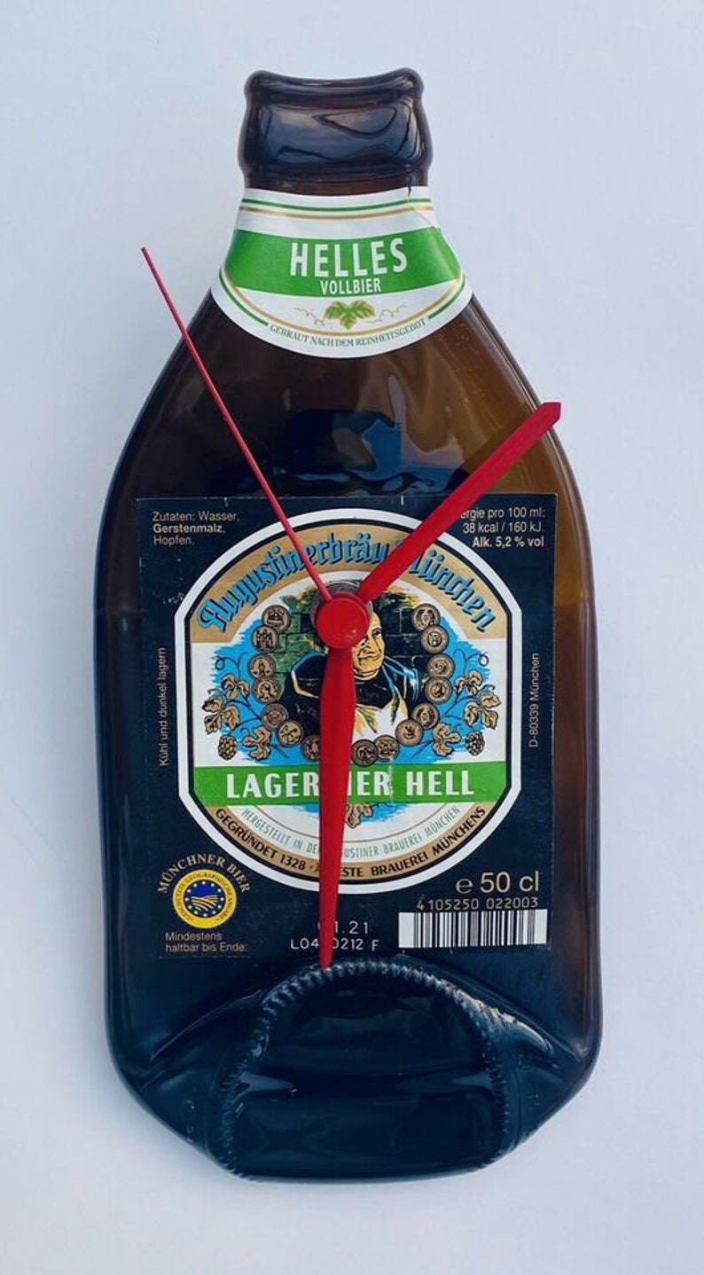 Puede incluir: Una botella de cerveza marr&oacute;n con una etiqueta verde y blanca que dice "HELLES VOLLBIER". La etiqueta tambi&eacute;n incluye el texto "Lager Hell" y "Augustiner-Br&auml;u M&uuml;nchen". Una esfera de reloj est&aacute; superpuesta.