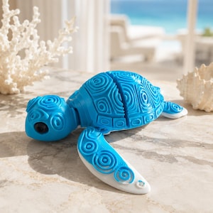 Può includere: Una tartaruga giocattolo blu brillante con un guscio dettagliato e decorato e arti articolati. La testa e gli arti della tartaruga sono blu unito, mentre le pinne sono bianche con dettagli blu. Il giocattolo è progettato con un motivo a spirale.