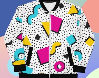 May include: A white bomber jacket featuring a black and white speckled pattern overlaid with colorful geometric shapes including pink rectangles, yellow triangles, and blue curved lines. The jacket has a black collar, cuffs, and hem with a front zipper.