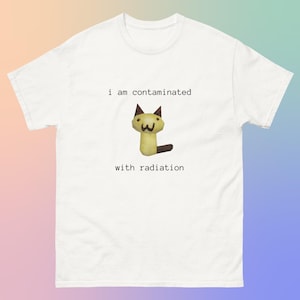 Puede incluir: Camiseta blanca con un gato de dibujos animados y el texto "i am contaminated with radiation".
