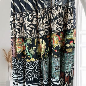 May include: A patchwork skirt with a variety of patterns, including floral, zebra stripes, and geometric designs. The skirt features a mix of black, white, and colorful fabrics, creating a bohemian style. The skirt is long and flowing, suitable for a casual or dressy occasion.