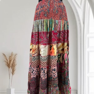 May include: A long, patchwork maxi dress with a vibrant mix of patterns and colors. The dress features a smocked bodice and a tiered skirt, showcasing a variety of floral, paisley, and abstract designs. The dress has a black strap and is suitable for casual wear.