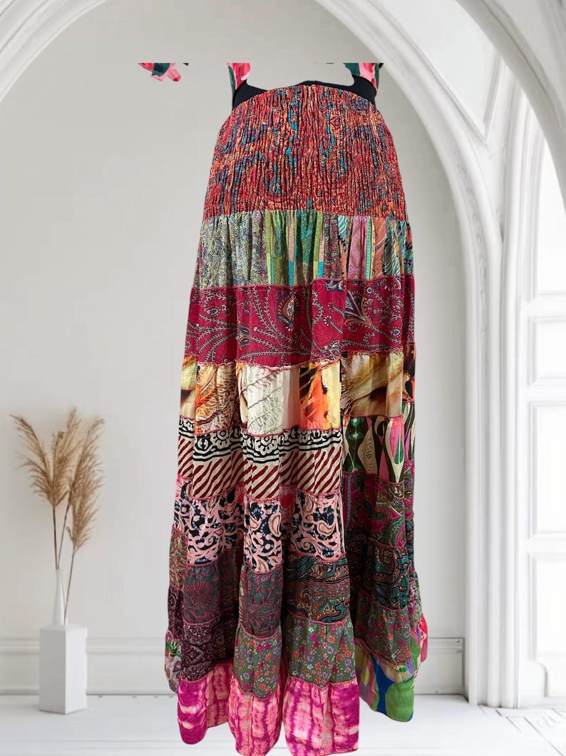 May include: A long, patchwork maxi dress with a vibrant mix of patterns and colors. The dress features a smocked bodice and a tiered skirt, showcasing a variety of floral, paisley, and abstract designs. The dress has a black strap and is suitable for casual wear.