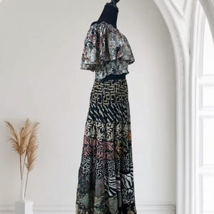 May include: A two-piece outfit on a mannequin. The top is a ruffled, off-the-shoulder style with a floral pattern in shades of blue, green, and red. The skirt is a patchwork design with various patterns and colors, including black, white, pink, and green.