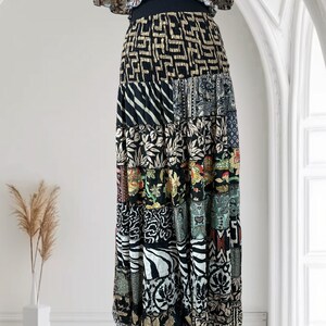 May include: A long, patchwork skirt with a variety of patterns and colors. The skirt features a black waistband and a tiered design with different fabric panels. The patterns include geometric shapes, floral prints, and zebra stripes. The top of the skirt has a ruffled design.