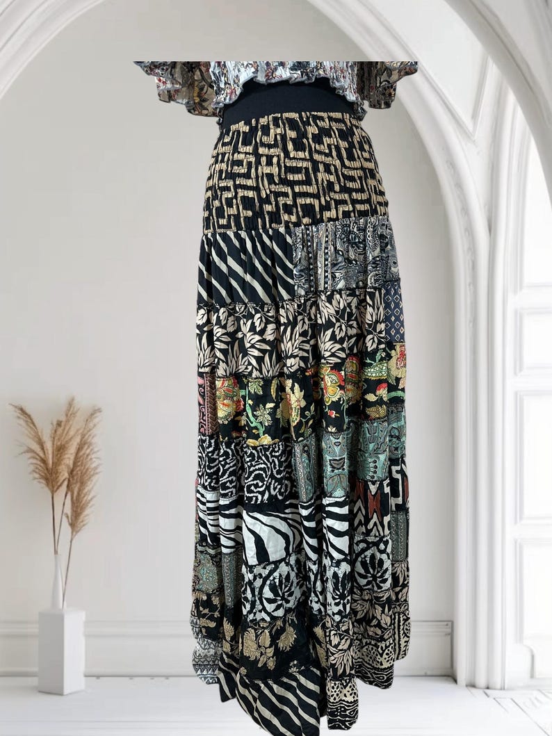 May include: A long, patchwork skirt with a variety of patterns and colors. The skirt features a black waistband and a tiered design with different fabric panels. The patterns include geometric shapes, floral prints, and zebra stripes. The top of the skirt has a ruffled design.