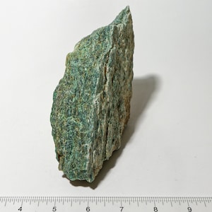 May include: A large, rough, green rock with a layered texture. The rock is about 7 inches tall and 4 inches wide.