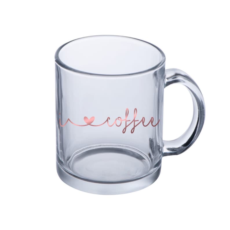 Puede incluir: Una taza de vidrio transparente con un dise&ntilde;o en oro rosa que dice "Me encanta el caf&eacute;".