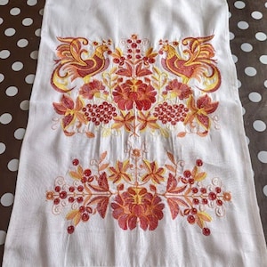 May include: White linen tea towel with red and yellow embroidered floral design and two birds. The towel has a red crocheted border.