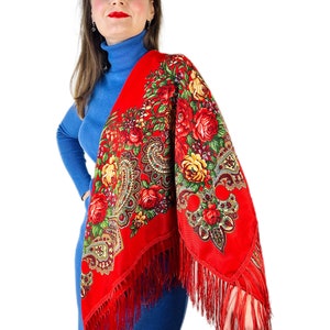 Peut inclure: Un ch&acirc;le rouge &agrave; motifs floraux et franges. Le ch&acirc;le est drap&eacute; sur les &eacute;paules d'une personne.