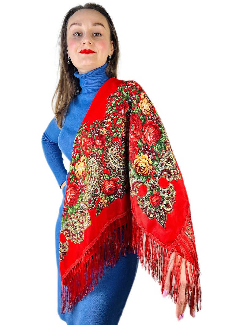 Peut inclure: Un ch&acirc;le rouge &agrave; motifs floraux et franges. Le ch&acirc;le est drap&eacute; sur les &eacute;paules d'une personne.