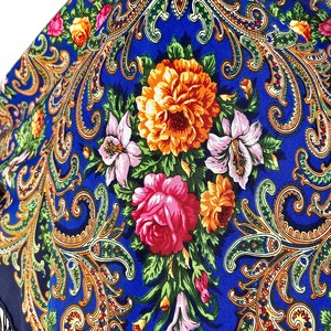 Peut inclure: Un foulard bleu &agrave; motifs paisley avec un motif floral compos&eacute; de fleurs roses, jaunes et orange. Le foulard a une bordure &agrave; franges.