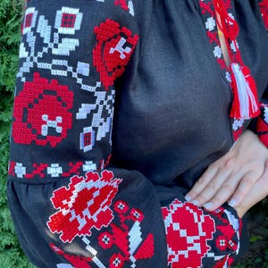 Puede incluir: Blusa de lino negra con patrones florales bordados en rojo y blanco. El bordado es de estilo ucraniano tradicional.