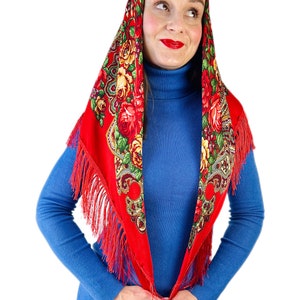 Peut inclure: Un foulard rouge &agrave; motifs floraux et franges. Le foulard est nou&eacute; autour de la t&ecirc;te et du cou, les extr&eacute;mit&eacute;s tombant sur le devant.