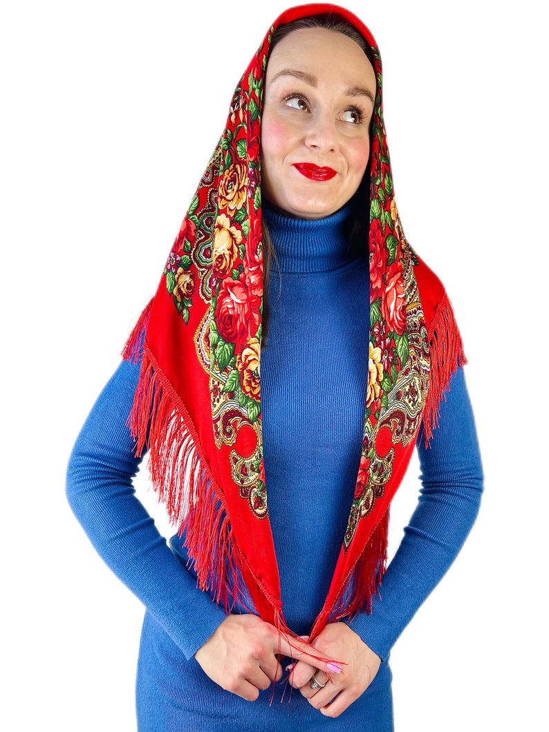 Peut inclure: Un foulard rouge &agrave; motifs floraux et franges. Le foulard est nou&eacute; autour de la t&ecirc;te et du cou, les extr&eacute;mit&eacute;s tombant sur le devant.