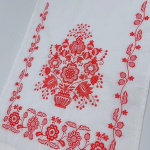 May include: White kitchen towel with red embroidered floral design. The design features a bouquet of flowers in a vase with a vine border.