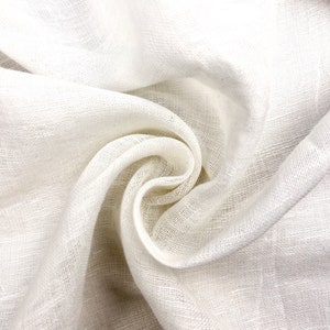 Puede incluir: Tela de lino blanco con una superficie suave y texturizada. La tela est&aacute; doblada y drapeada, creando un aspecto suave y fluido.