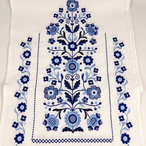 May include: White linen tea towel with blue and black embroidered floral design. The design features a central floral motif with smaller floral motifs along the sides.