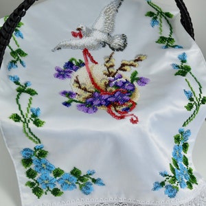 May include: White satin basket liner featuring a beaded design of a dove, flowers, and an egg. The liner has a white lace trim.