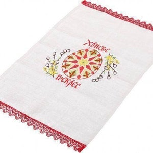 Peut inclure: Serviette de cuisine blanche brod&eacute;e avec une bordure en dentelle rouge. La serviette pr&eacute;sente un motif d'&oelig;uf de P&acirc;ques color&eacute; et le texte "Христос Воскрес" en cyrillique.