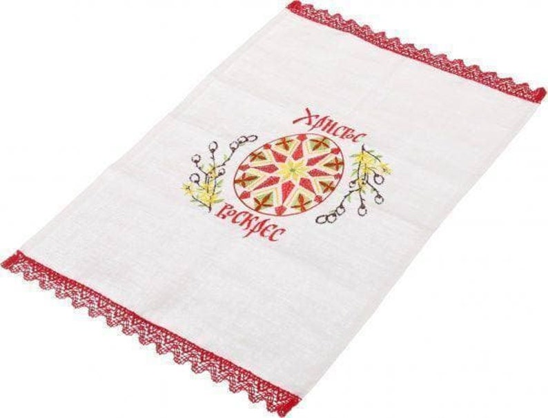Peut inclure: Serviette de cuisine blanche brod&eacute;e avec une bordure en dentelle rouge. La serviette pr&eacute;sente un motif d'&oelig;uf de P&acirc;ques color&eacute; et le texte "Христос Воскрес" en cyrillique.