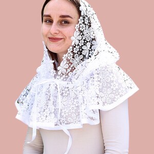 May include: White lace mantilla with a scalloped edge and a bow tie. The mantilla is worn over the head and shoulders.