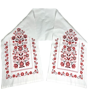 K&ouml;nnte beinhalten: Ein wei&szlig;er Tischl&auml;ufer aus Stoff mit roten und schwarzen gestickten Blumendesigns. Der L&auml;ufer ist in der Mitte gefaltet und hat ein schlichtes, elegantes Design.