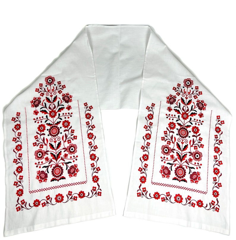 K&ouml;nnte beinhalten: Ein wei&szlig;er Tischl&auml;ufer aus Stoff mit roten und schwarzen gestickten Blumendesigns. Der L&auml;ufer ist in der Mitte gefaltet und hat ein schlichtes, elegantes Design.