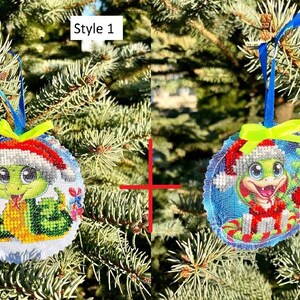 May include: Two Christmas ornaments featuring a green turtle wearing a Santa hat. The ornament on the left has a white background with a green Christmas tree and red ornaments. The ornament on the right has a blue background with red and white candy canes. The ornaments are labeled "Style 1" and "Style 2".