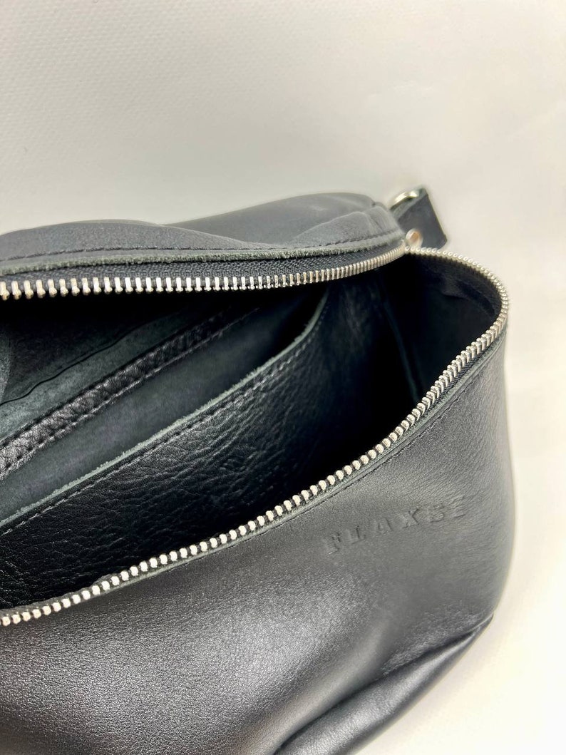 May include: Black leather zippered pouch with a silver zipper and the word "WAKESE" embossed on the bottom.