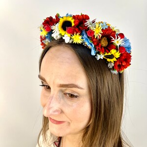 Pode incluir: Uma faixa de cabe&ccedil;a floral com flores vermelhas, amarelas e azuis. A faixa de cabe&ccedil;a &eacute; feita de flores de tecido e &eacute; perfeita para um festival de ver&atilde;o ou um casamento.