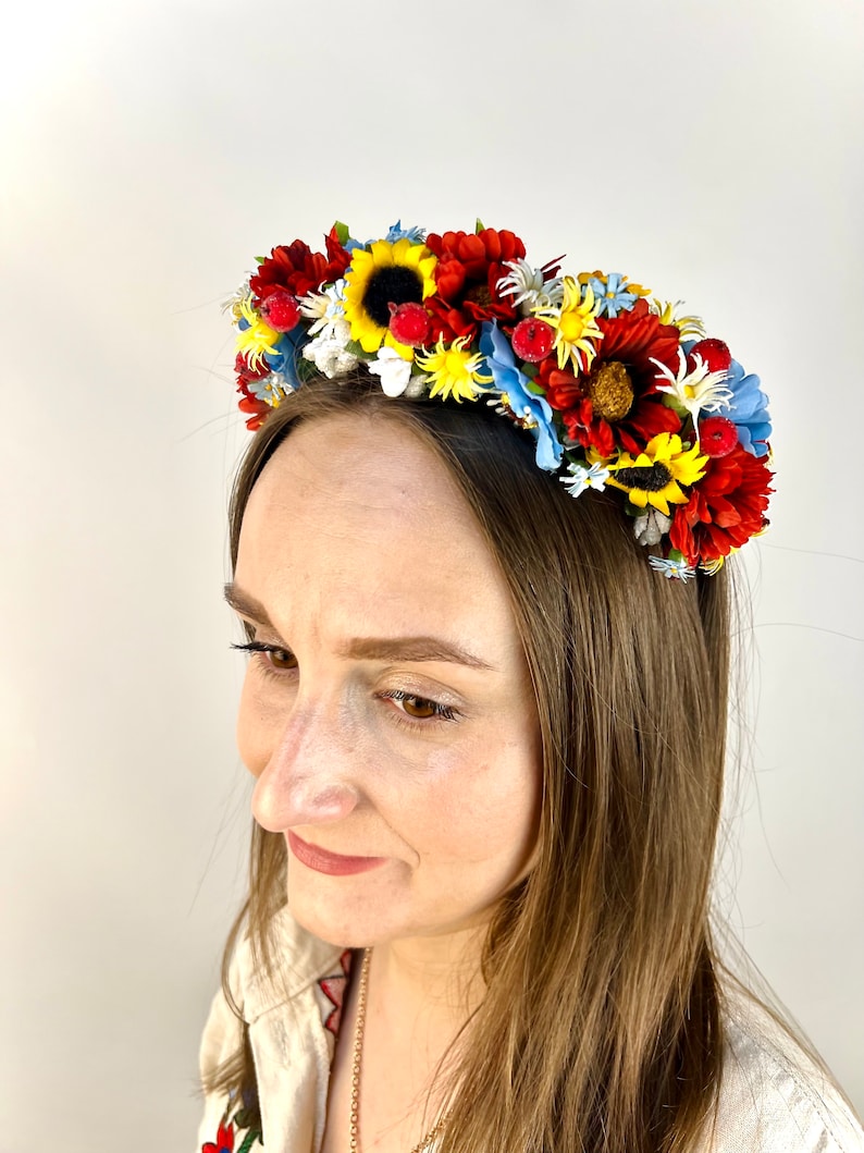 Pode incluir: Uma faixa de cabe&ccedil;a floral com flores vermelhas, amarelas e azuis. A faixa de cabe&ccedil;a &eacute; feita de flores de tecido e &eacute; perfeita para um festival de ver&atilde;o ou um casamento.