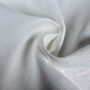 May include: White linen fabric with a textured weave. The fabric is folded and draped, showing its soft and smooth texture.
