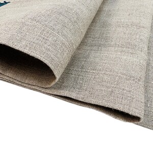 Op de afbeelding: Close-up van een gevouwen stuk beige linnen stof met een textuurweefsel.