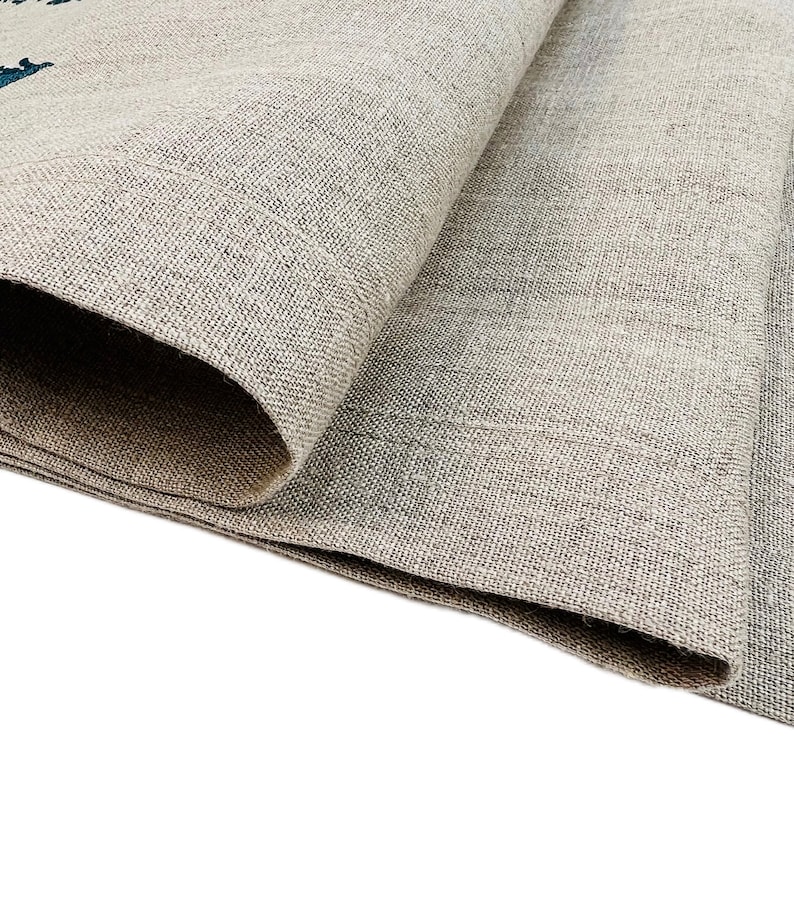 Op de afbeelding: Close-up van een gevouwen stuk beige linnen stof met een textuurweefsel.