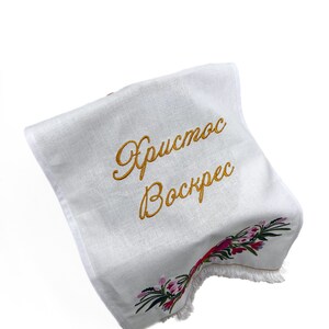 Pu&ograve; includere: Asciugamano da t&egrave; in lino bianco con un messaggio ricamato in oro che recita "Христос Воскрес" (Cristo &egrave; risorto) e un motivo floreale ricamato in rosa, rosso e verde.