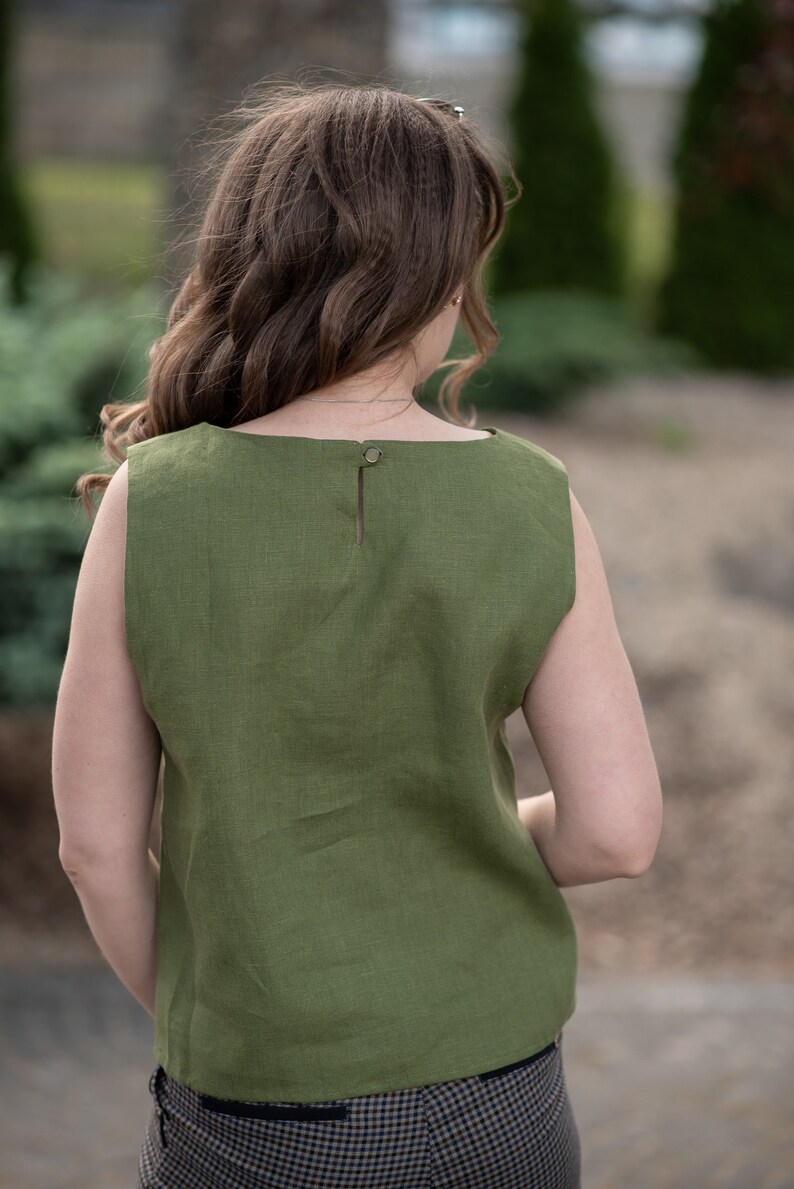 May include: A sleeveless green linen top with a button closure at the back of the neck.