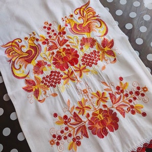 May include: White linen tea towel with red and yellow embroidered floral design featuring two stylized birds. The embroidery includes a floral pattern with berries and leaves.