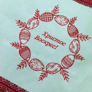 May include: A light blue fabric with red embroidered Easter eggs and the text "Хриcтоc Воскрес!" which translates to "Christ is Risen!" in English.