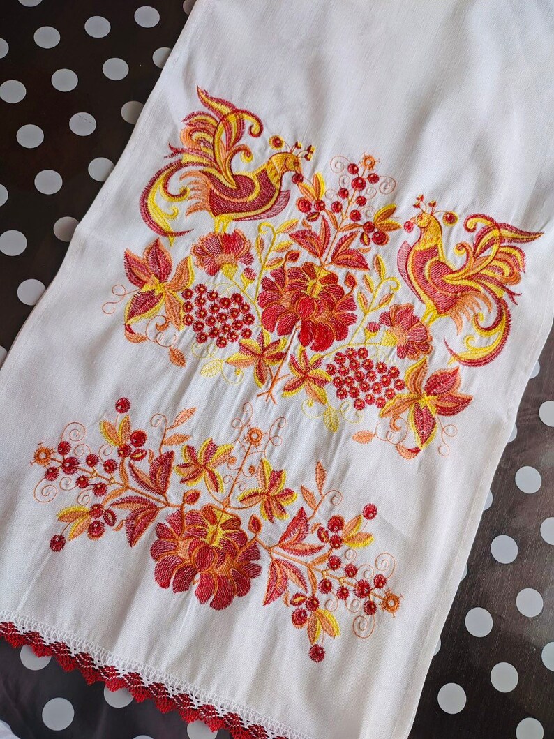 May include: White linen tea towel with red, orange, and yellow embroidered birds and floral designs.