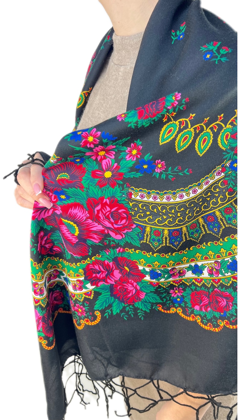Pu&ograve; includere: Uno scialle nero con un motivo floreale colorato e frange. Il motivo comprende fiori rossi, rosa, gialli, blu e verdi.