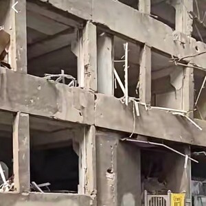 K&ouml;nnte beinhalten: Au&szlig;enansicht eines besch&auml;digten Betongeb&auml;udes mit mehreren offenen Fensterrahmen. Die Struktur weist erhebliche Sch&auml;den auf, mit sichtbaren Rissen und fehlenden Abschnitten. Die Uhrzeit 14:05 ist oben links sichtbar.