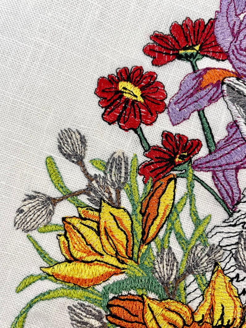 May include: Embroidered floral design featuring yellow, orange, and red flowers with green leaves and stems on a white background.