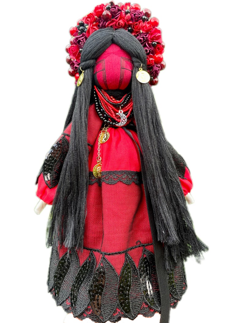 Puede incluir: Una mu&ntilde;eca de tela roja con cabello negro, que lleva un vestido rojo con ribete de encaje negro y una corona de flores rojas en la cabeza.