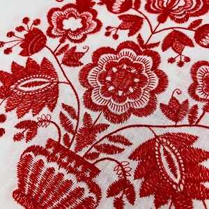 May include: Red embroidered floral design on a white fabric background. The design features a vase with flowers and leaves.