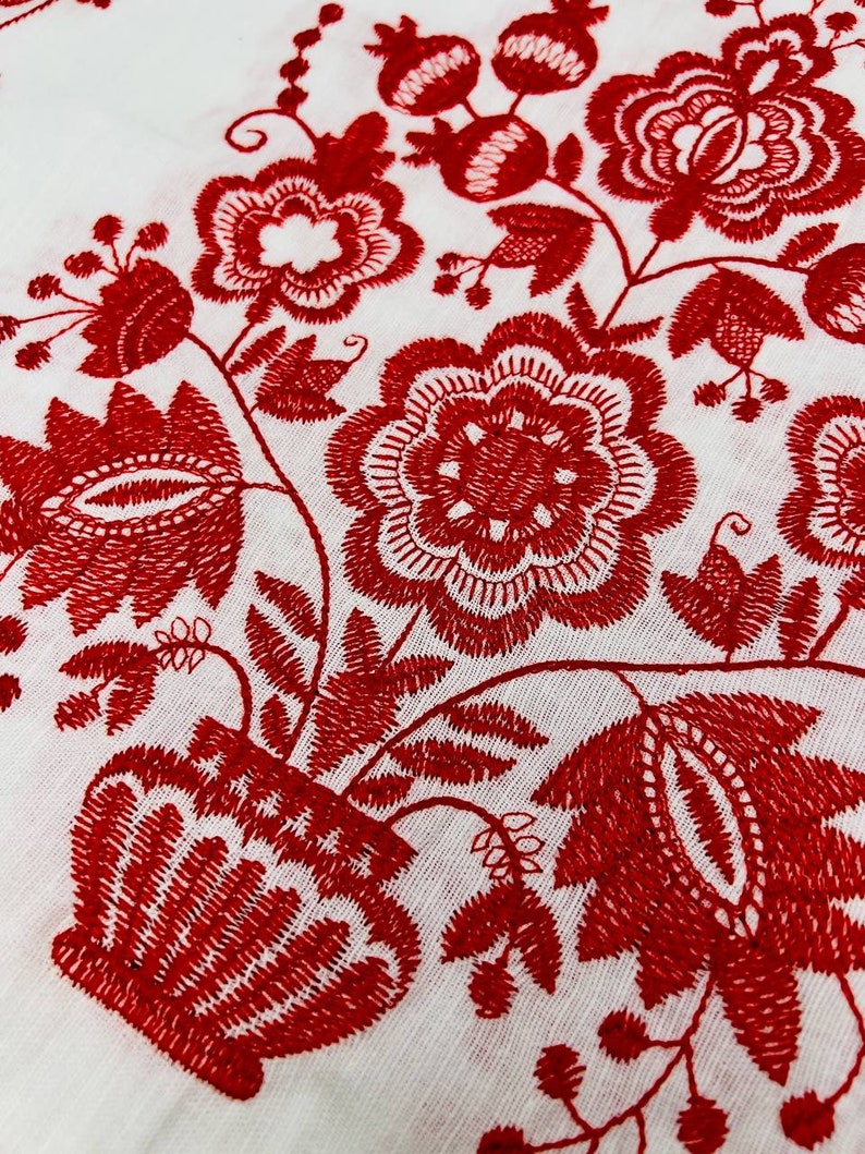 May include: Red embroidered floral design on a white fabric background. The design features a vase with flowers and leaves.